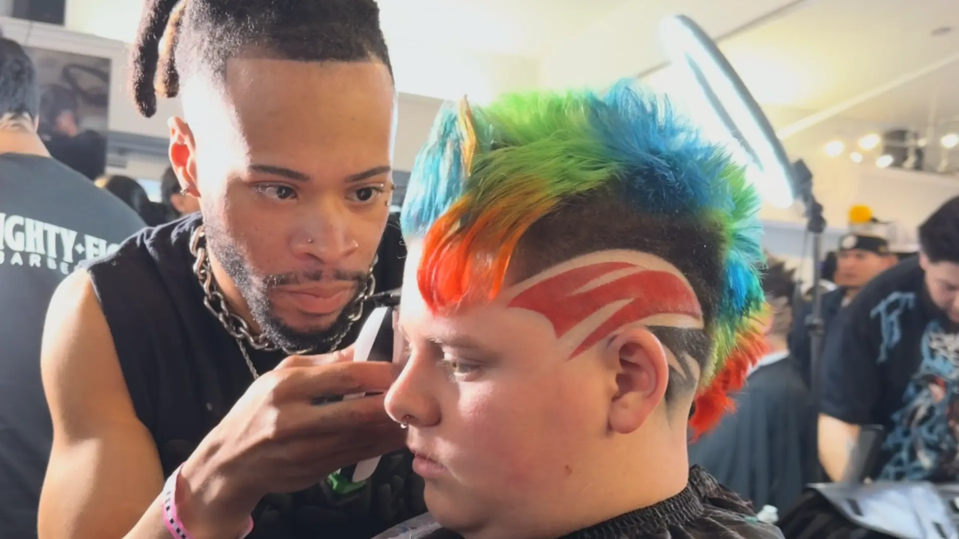 Barber refining a colorful sculpted haircut at a barber event