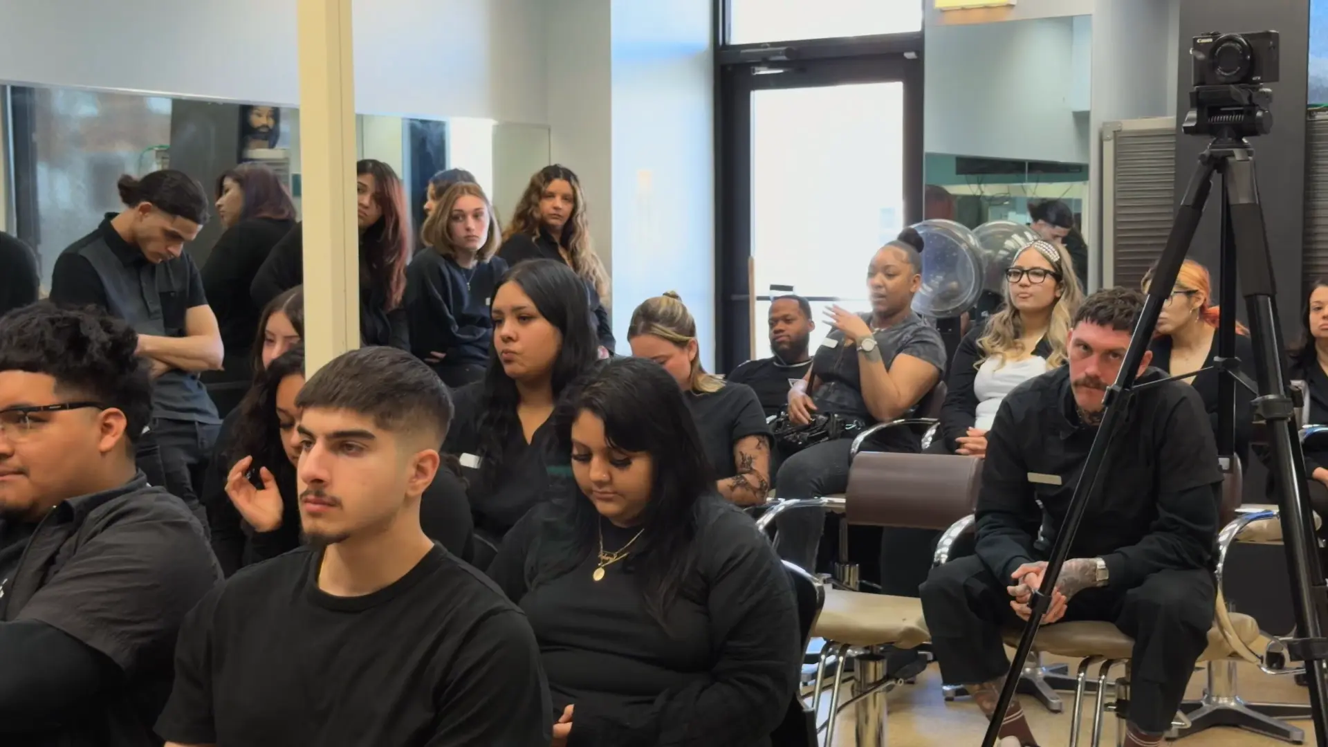 Attendees watching a barber education class with a camera set up to record